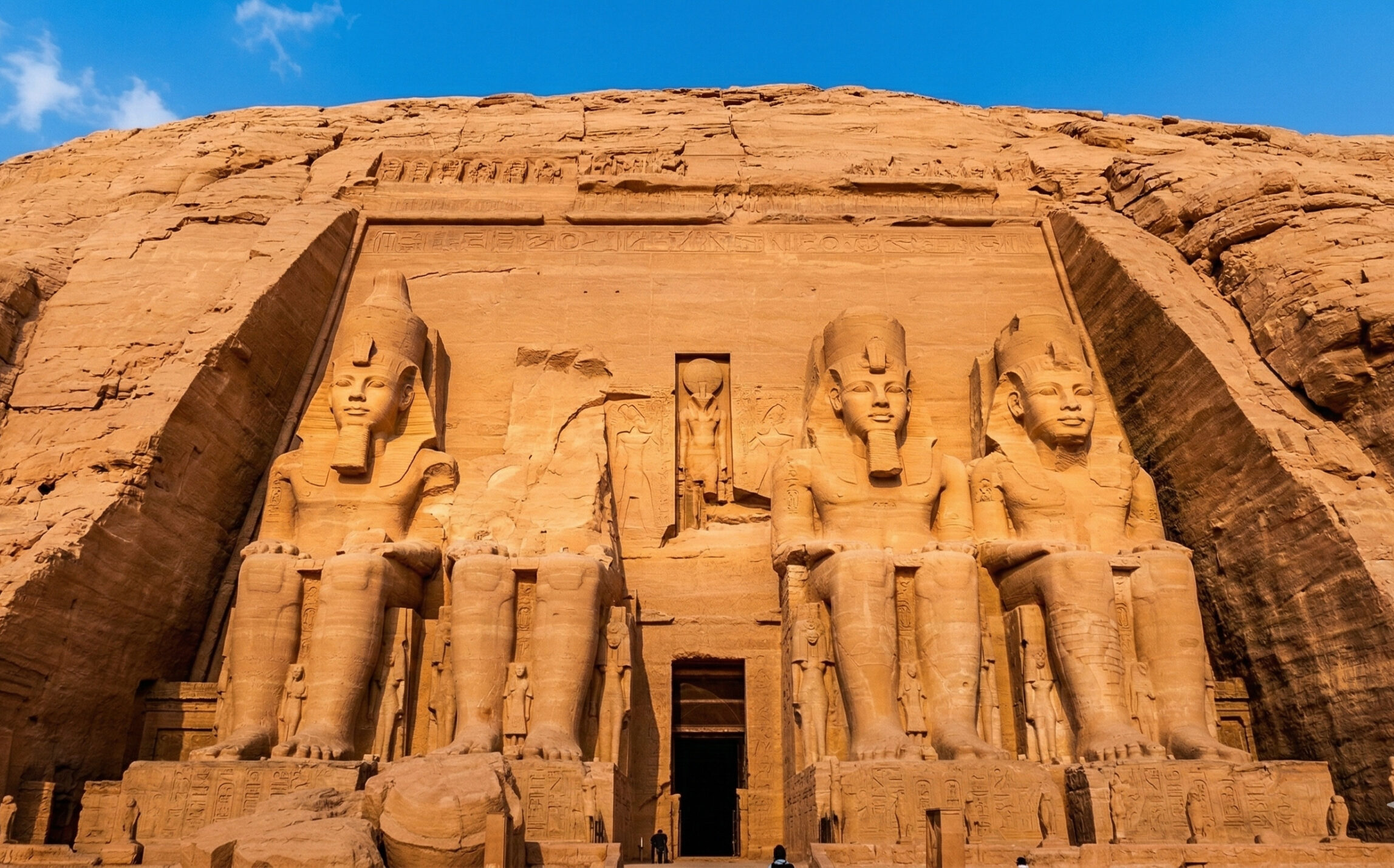 The four colossal rock-cut seated statues of Pharaoh Ramses II on the facade of the Great Temple of Abu Simbel at sunrise.
