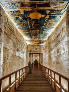 Visitors walking down an illuminated painted tomb corridor in the Valley of the Kings on a Hurghada to Luxor VIP day trip.